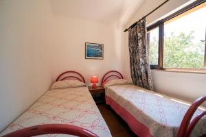 two twin beds in a room with a window at Appartamento Laura in Porto Azzurro