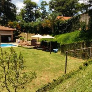 un patio con sombrilla y piscina en Chácara em Atibaia, en Atibaia