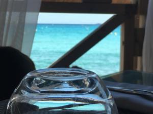 - une bouteille de verre assise sur une table avec vue sur l'océan dans l'établissement Restaurant - Chambres d'Hôtes Terra Bella Lecci, à Porto-Vecchio