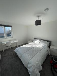 a white bedroom with a large bed and a window at Double room with private bathroom in Basingstoke in Basingstoke