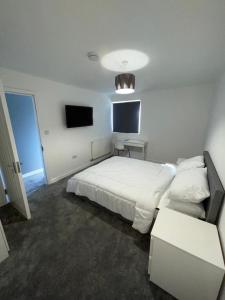 una camera con letto bianco e TV di Double room with private bathroom in Basingstoke a Basingstoke