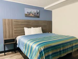 a bedroom with a bed with a colorful striped blanket at Crown Inn Motel in Linden