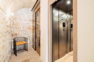 a hallway with a metal elevator and a stone wall at BAYIT Charming Place in Polignano a Mare
