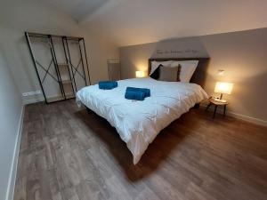a bedroom with a large bed with two blue pillows on it at "Le petit bonheur" Gîte van 4 tot 12 personen met privé vijver van 2Ha in Maisonnais-sur-Tardoire
