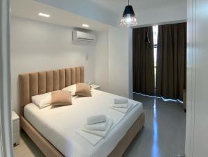 a bedroom with a bed with white sheets and pillows at City Glow Apartments in Sarandë