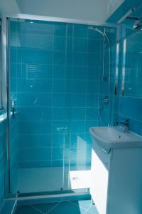 baño azul con ducha y lavamanos en Punta Lingua Relais- Room 1 Sunrise Terrace, en Procida