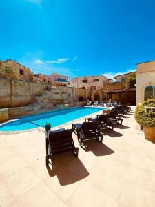 a row of chairs sitting next to a swimming pool at Velver Mansion, Malta - Luxury Villa with Pool in Naxxar