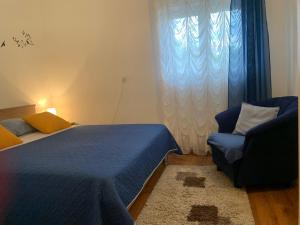 a bedroom with a bed and a chair and a window at Apartman ABO*** in Komin