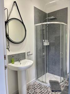 a bathroom with a sink and a shower with a mirror at The Gallery At Warrenfield House in Kirkwall