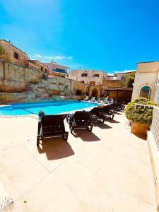 納克薩的住宿－Velver Mansion, Malta - Luxury Villa with Pool，游泳池旁的一排椅子