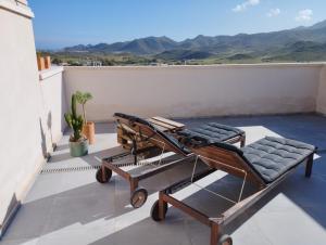 a pair of lounge chairs on a balcony with mountains at Luz del Cabo in El Pozo de los Frailes