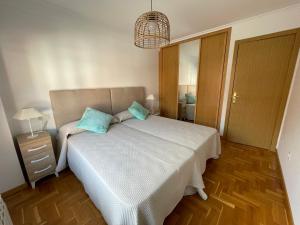 a bedroom with a white bed with blue pillows at Apartamento Turistico Mirador de Valdellera I in Posada de Llanes