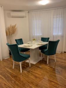 a white dining room table with green chairs at Magnificat Apartment Medjugorje in Međugorje