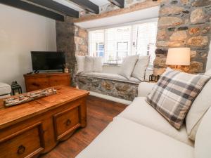 a living room with white furniture and a stone wall at Penhale Cottage in Marazion