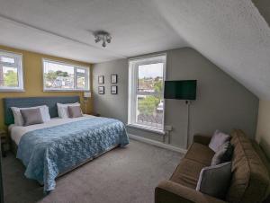 a bedroom with a bed and a couch and two windows at Redlands in Brixham