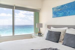 a bedroom with a bed and a large window with the ocean at Ocean View Three Bedroom, Three Story Penthouse by the Beach in Cancún