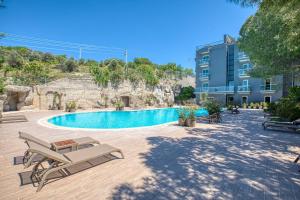 a resort with a pool and chairs and a building at AEGEAN Apartments - Çeşme in Cesme