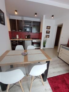 een keuken met een houten tafel en witte stoelen bij MK Apartament II in Rzeszów