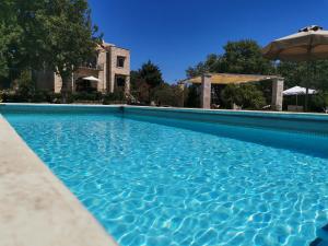 una piscina con ombrellone di fronte a una casa di Villa Ermis - The Cretan Castello a Kástellos