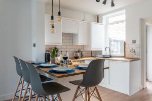 een keuken met witte kasten en een tafel met stoelen bij Elmwood Cottage - Harrogate in Harrogate