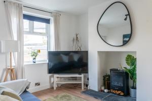 un soggiorno con TV a schermo piatto e specchio di Elmwood Cottage - Harrogate a Harrogate