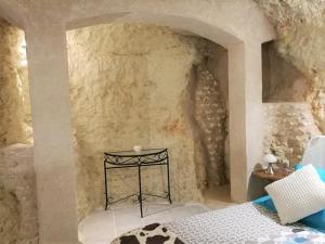 ein Schlafzimmer mit einem Bett in einer Steinmauer in der Unterkunft Cave du Coteau 2 in Lunay