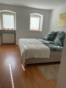 a bedroom with a large bed and two windows at Ferienwohnung Dorfperle in Bad Mergentheim