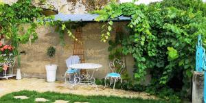 a patio with a table and chairs in a garden at Cave du Coteau 2 in Lunay