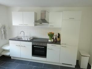 a white kitchen with a sink and a stove at Ferienwohnung Dorfperle in Bad Mergentheim