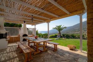 a patio with a table and benches and a view at Villa Pasiphae in Kranidi