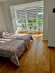 ein Schlafzimmer mit einem Bett und Stühlen sowie einem großen Fenster in der Unterkunft Vilniaus 96 apartments in Ukmergė