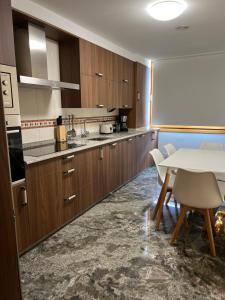 a kitchen with wooden cabinets and a white table and chairs at Apartamentos vacaciones Rio Lever in Boiro