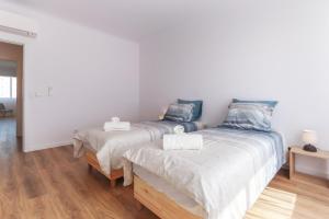 twee bedden in een kamer met witte muren en houten vloeren bij Vita Portucale ! Costa da Caparica Sunny Design Apartment in Costa da Caparica