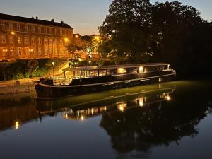a boat on a river in front of a building at Savy Hôtel in Verdun