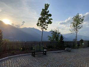 a bench sitting on a brick walk way with the sunset at Urige Ferienwohnung Steiger- Alloggio unico Steiger in Bressanone