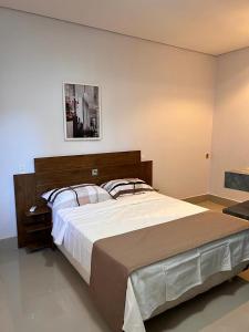 1 dormitorio con 1 cama grande y una foto en la pared en Suites Stival Centro, en Goiânia
