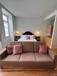 a couch with pink pillows in a room with a bed at Pensao O Laranjeira in Viana do Castelo