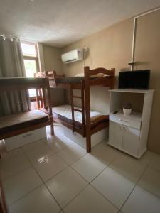 Pokój z 2 łóżkami piętrowymi i telewizorem w obiekcie Apraiana Hostel w mieście Recife