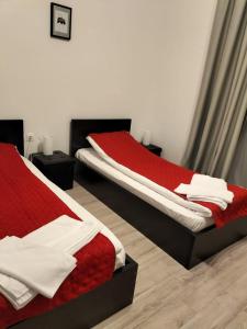 una camera con due letti con lenzuola rosse e bianche di Pensiunea CASA SPANDO a Mărişel