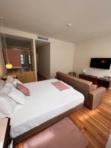a bedroom with a large bed and a couch at Pensao O Laranjeira in Viana do Castelo