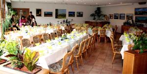 a dining room with white tables and chairs with plants at Hotel & Restaurant Bergfried in Saalfeld