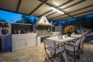 an outdoor kitchen with a white table and chairs at Antigoni's Family House! in Zakynthos