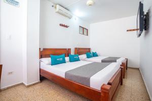 a bedroom with two beds with blue pillows at Ayenda William Sanchez in Apartadó
