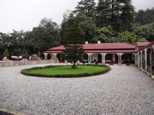 un edificio con un árbol en medio de un patio en The Claridges Nabha Residence, en Mussoorie