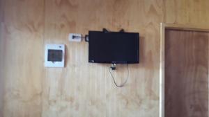 TV de pantalla plana colgada en la pared en Cabañas Claire en El Quisco