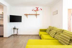 uma sala de estar com um sofá amarelo e uma televisão em Casa Avenida del Agujero em Gáldar