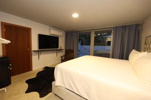 een slaapkamer met een wit bed en een televisie bij Viento Beach Lodge in Dorado
