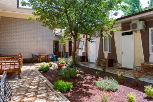 タシュケントにあるHotel & Hostel Galleryの家の前に木とベンチのあるパティオ