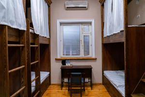 タシュケントにあるHotel & Hostel Galleryのデスク、窓、二段ベッドが備わる客室です。