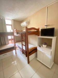 a small room with two bunk beds and a television at Apraiana Hostel in Recife